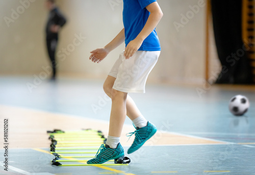 Young boy at sports training at indoor court ladder drill. Futsal training session for school kids