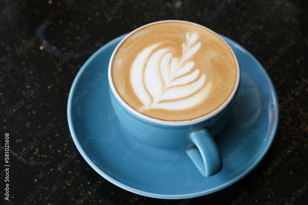 A cup of cappuccino served on an artistic black table A cup of cappuccino served on an artistic black table