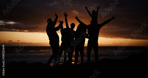 Freedom  sunset and silhouette of people at the beach while on a summer vacation  adventure or weekend trip. Carefree  happy and shadow of group of friends having fun together by the ocean on holiday