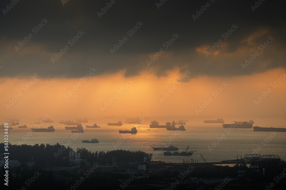 Sunrise over Singapore harbour with a lot of ships waiting on the sea line. Cargo vessel transportation industry by water aerial view.