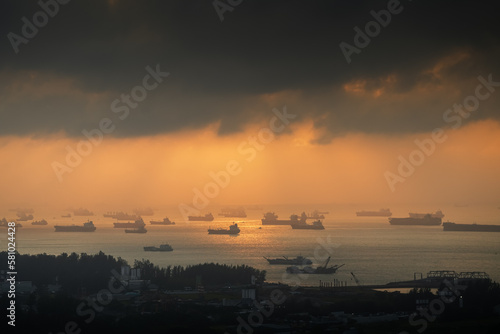 Sunrise over Singapore harbour with a lot of ships waiting on the sea line. Cargo vessel transportation industry by water aerial view.