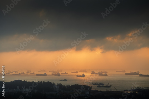 Sunrise over Singapore harbour with a lot of ships waiting on the sea line. Cargo vessel transportation industry by water aerial view.