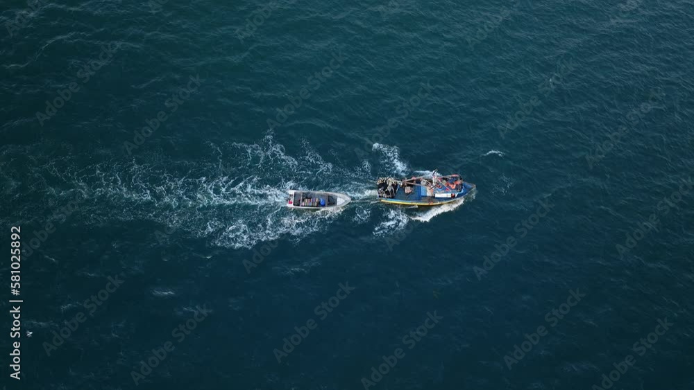 Aerial Birds Eye View Of Motorised Fishing Boat Sailing Across Waters Off Pacific Ocean With Birds Flying Overhead. Tracking Shot Aerial Birds Eye View Of Motorised Fishing Boat Sailing Across Waters Off Pacific Ocean With Birds Flying Overhead. Tracking Shot