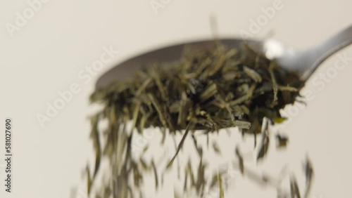 A Pile of green tea laeves is falling of a spoon in 100 FPS. Close-up shot. photo