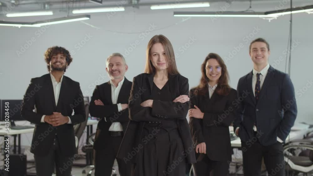Business partners hold a group photo session in the office. A woman with folded hands stands in front of her colleagues. The concept of a successful business team. Business partners hold a group photo session in the office. A woman with folded hands stands in front of her colleagues. The concept of a successful business team.
