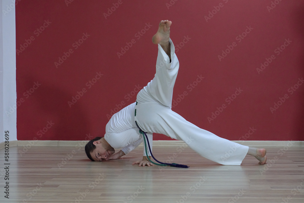 A mature man, a master, demonstrates the acrobatic exercises of the Brazilian martial art of capoeira. Demonstration of movements for students.