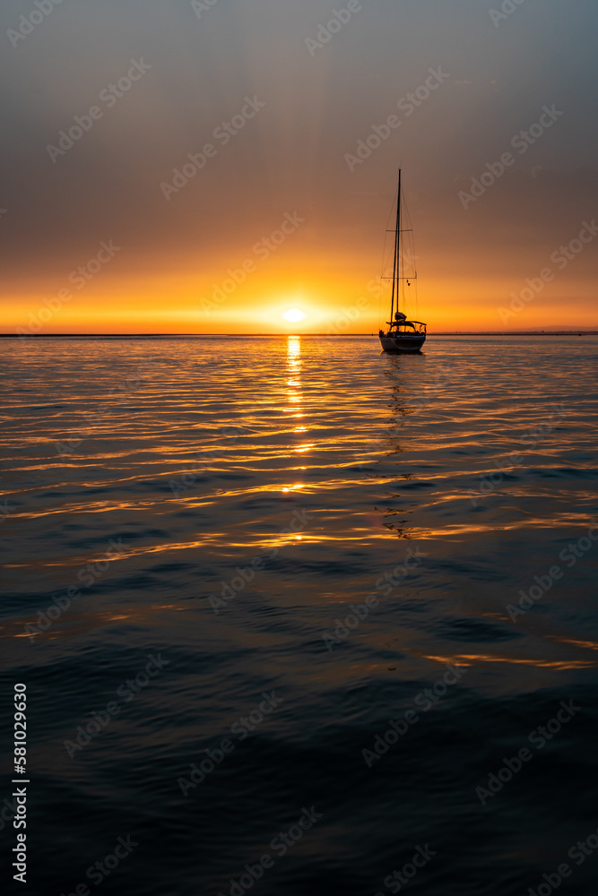 sailboat sailing in the sea on the right side of the sunset. vertical photo with copy space sailboat sailing in the sea on the right side of the sunset. vertical photo with copy space