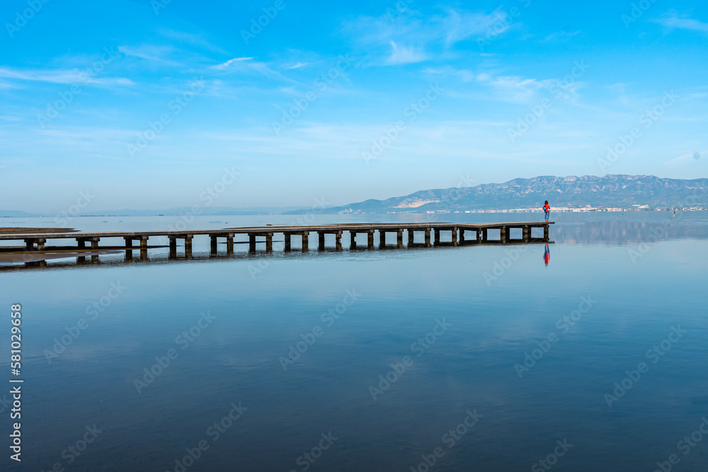 woman on pier looking at the horizon in the Ebro Delta, Spain. horizontal photograph with copy space.