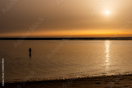 silhouette of woman walking on the beach during sunset. horizontal photograph with copy space.