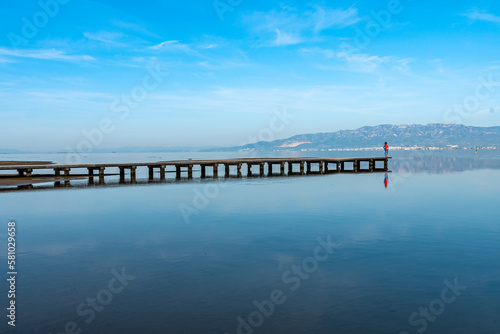 woman on pier looking at the horizon in the Ebro Delta, Spain. horizontal photograph with copy space. © pulinosa