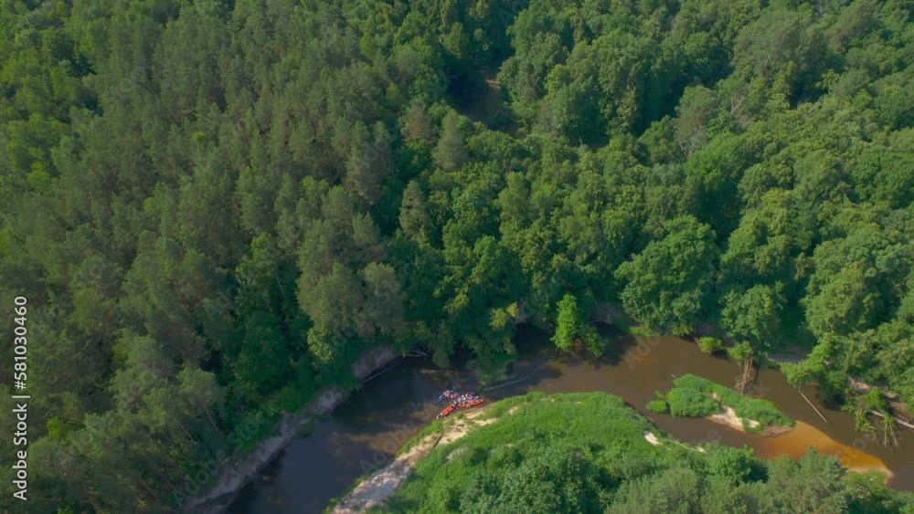 A group of tourist kayaks with tourists swim a sharp turn on a narrow wild river flowing through a dense green forest. Taken from a flying drone. The concept of kayaking on wild rivers A group of tourist kayaks with tourists swim a sharp turn on a narrow wild river flowing through a dense green forest. Taken from a flying drone. The concept of kayaking on wild rivers