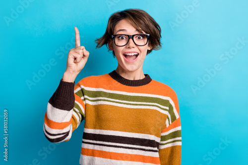 Photo of excited funky lady wear striped sweater spectacles pointing up empty space isolated blue color background