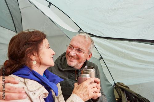 Elderly couple having tea together sitting in tent