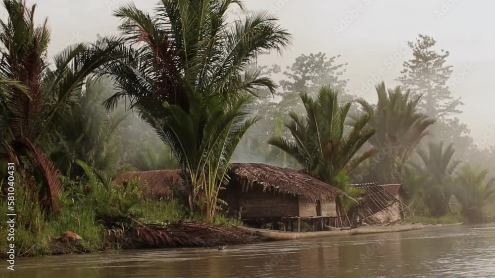 Indigenous huts on the river in the jungle in Papua - shot from a canoe Indigenous huts on the river in the jungle in Papua - shot from a canoe