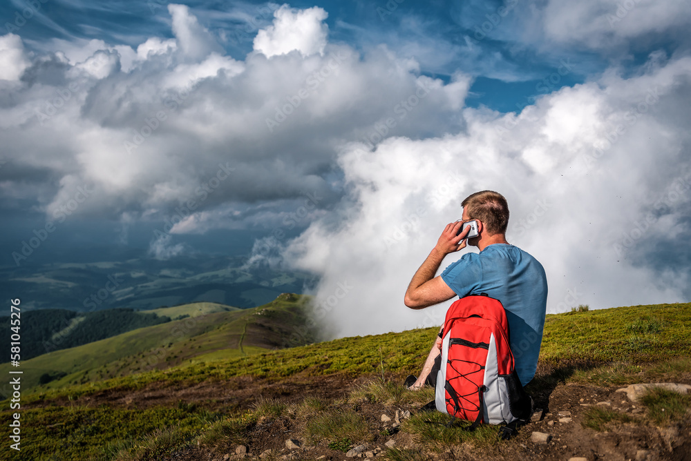 Naklejka premium Backpacker calling with mobile phone in highland of mountains
