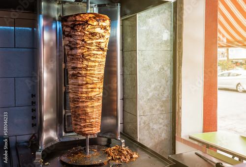Rotating spit for making traditional turkish street food Doner Kebab on table in a street food shop photo