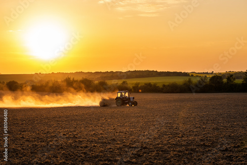 Tractor preparing farmland with seedbed for the next year at sunset