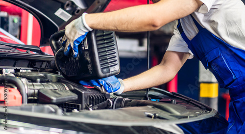 Professional car technician mechanic team in uniform work fixing vehicle car engine and maintenance repairing checking under the car hood in auto service. Automobile service garage