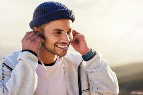 Man with earphones, listening to music and smile outdoor with runner, fitness and motivation with radio streaming. Podcast, technology and exercise at sunset, happy male and running, audio and sport