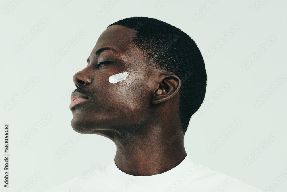 Young black man taking care of his skin with nourishing face cream Young black man taking care of his skin with nourishing face cream