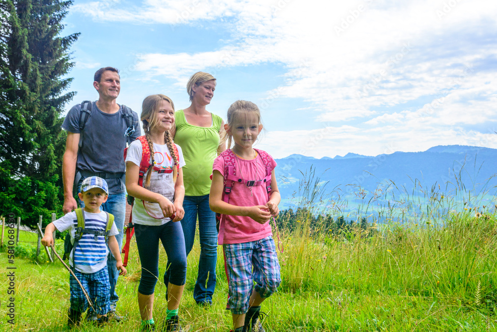 Ausflug ins Grüne mit der Familie, gemeinsame Wanderung auf einem Pfad inmitten einer blühenden Bergwiese Ausflug ins Grüne mit der Familie, gemeinsame Wanderung auf einem Pfad inmitten einer blühenden Bergwiese