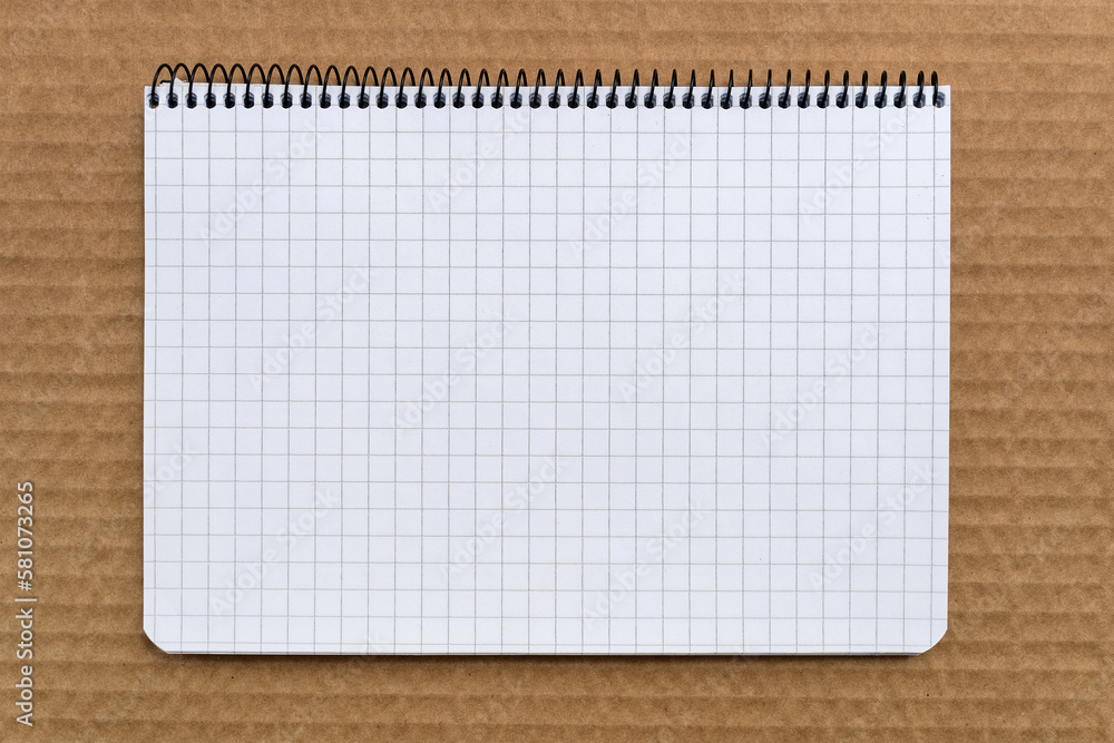 Graph paper spiral Notebook on top of brown cardboard Graph paper spiral Notebook on top of brown cardboard