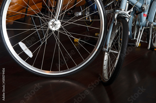 Bright bicycle wheels and refection on glossy wooden floor