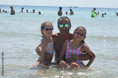 Papà al mare d'estate con figlie gemelle di 8 anni.