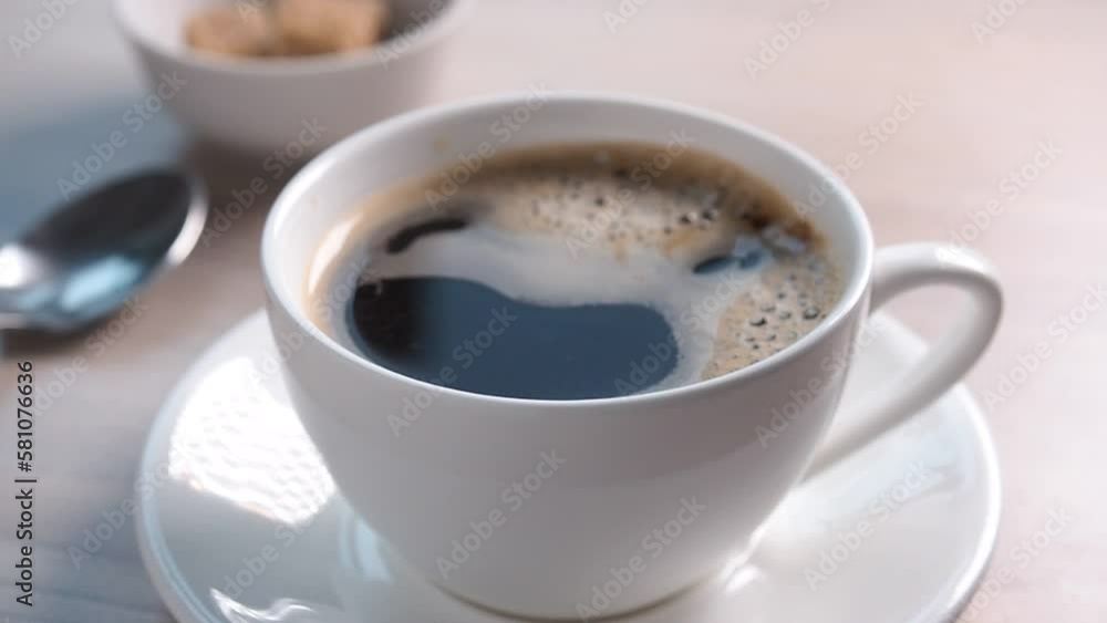 Pour boiling water in a cup of instant coffee. Coffee cup and saucer on the table, top view. Pour boiling water in a cup of instant coffee. Coffee cup and saucer on the table, top view.