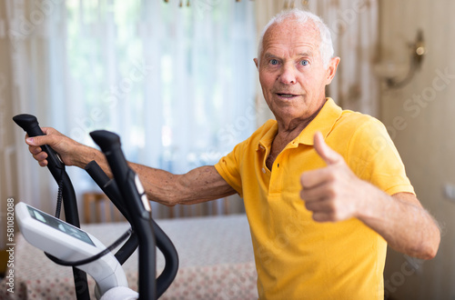 Senior man with elliptical trainer at home