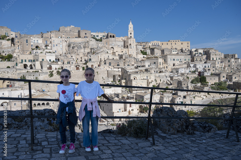 Ritratto di due sorelle gemelle di 8 anni con allo sfondo la città di Matera.
