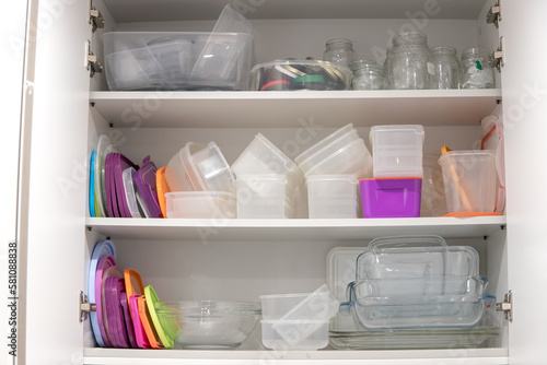 Fotografija Open kitchen cupboard full of plastic and glass containers inside