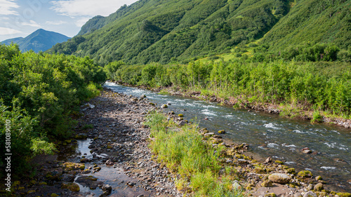 Blue river flows under an azure sky. A sunny summer day. Kamchatka