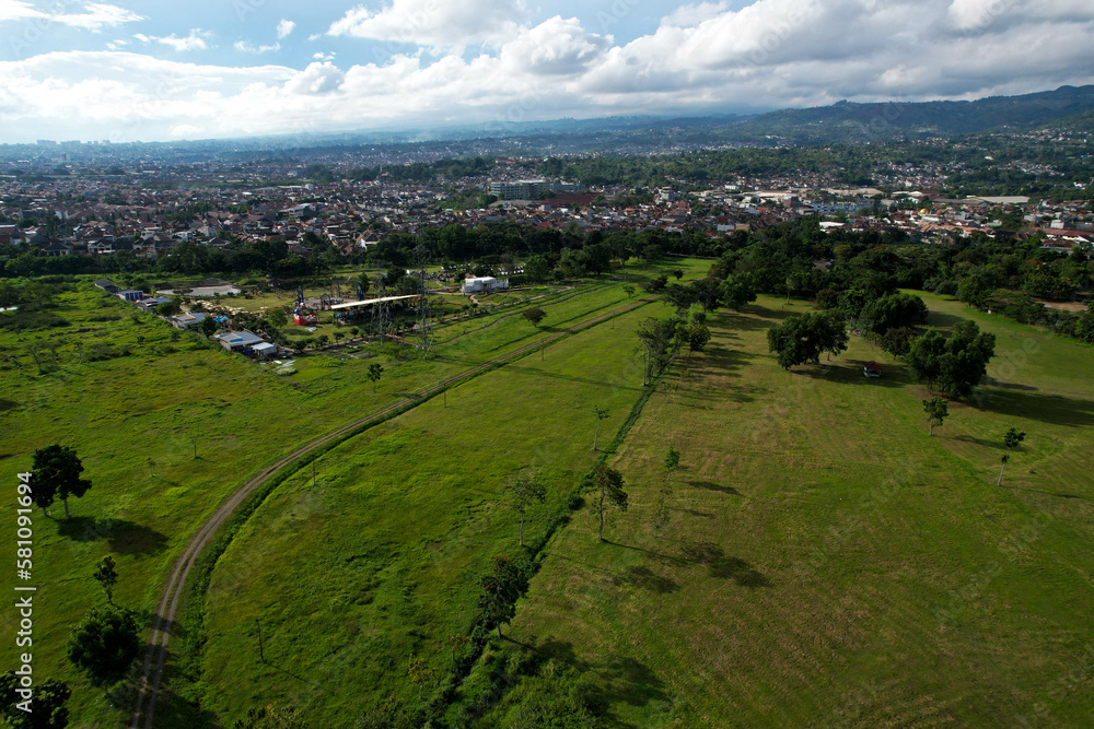 Aerial view of wide green fields side by side with urban settlements and mountains