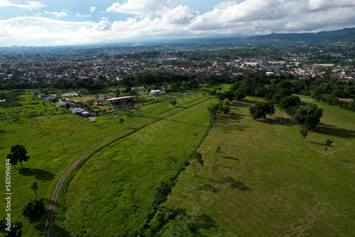 Aerial view of wide green fields side by side with urban settlements and mountains
