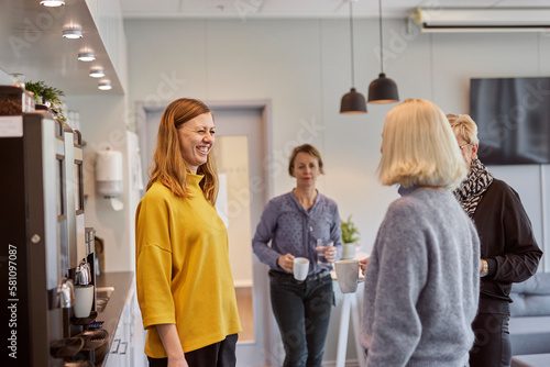 Women talking in office kitchen photo