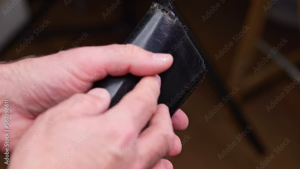 A man pulls out of his wallet and counts money in euros. View of the man's hands. A man pulls out of his wallet and counts money in euros. View of the man's hands.