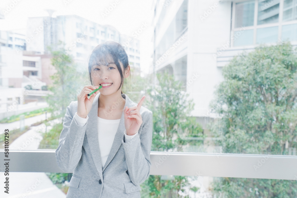 電子タバコを吸う若いビジネスウーマン 電子タバコを吸う若いビジネスウーマン
