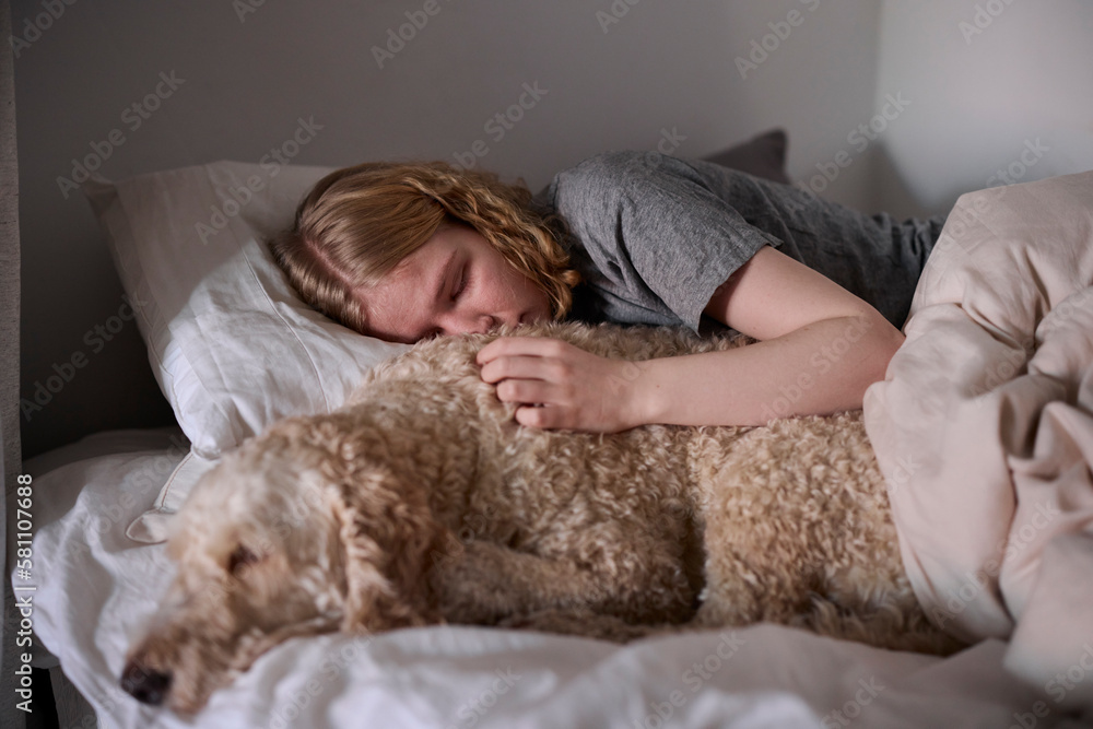 Crying young woman hugging dog in bed Crying young woman hugging dog in bed