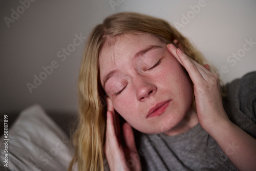 Young woman touching temples with closed eyes