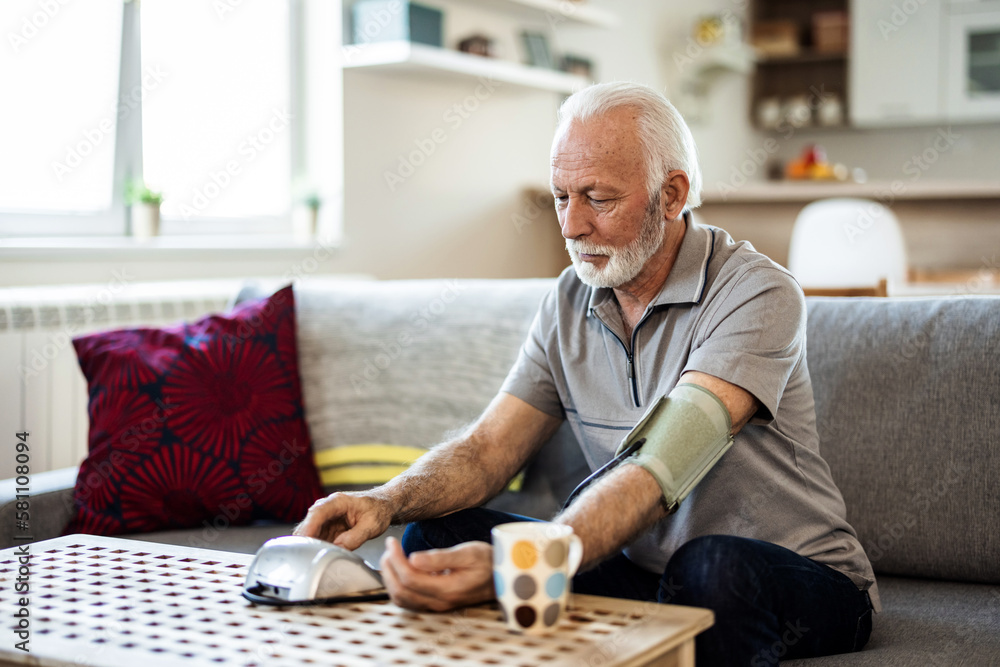 Senior checking his blood pressure. Senior man examining blood pressure in bedroom at home during the day. Senior checking his blood pressure. Senior man examining blood pressure in bedroom at home during the day.