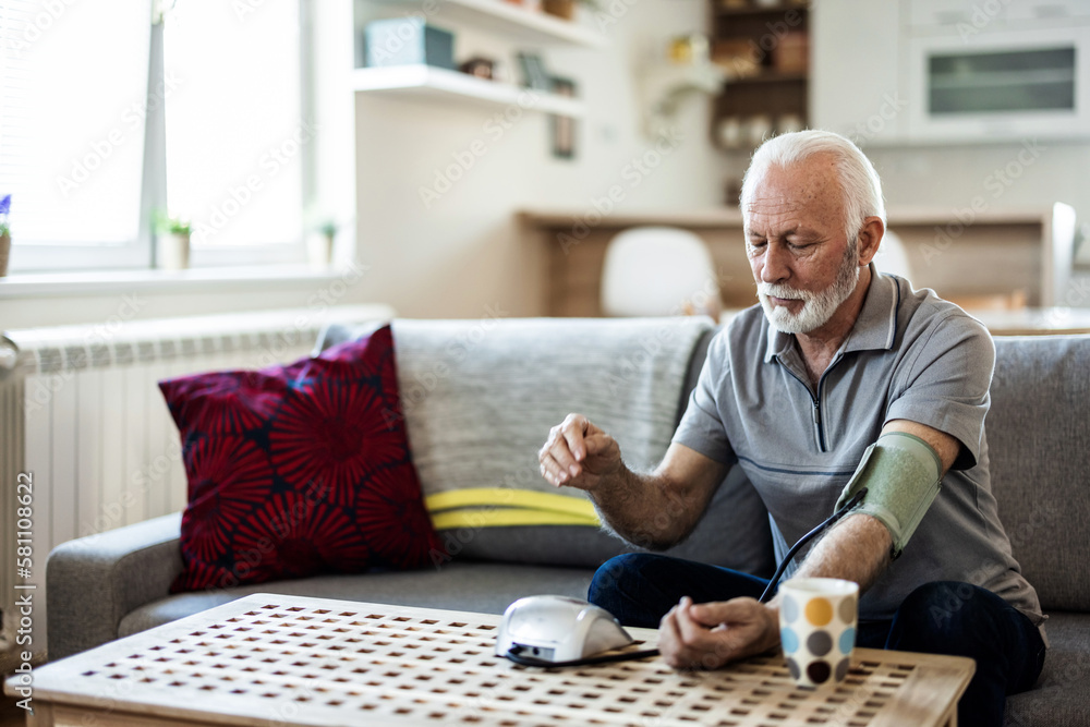 Senior man using medical device to measure blood pressure. Shot of a senior man using a blood pressure monitor at home. Senior man using medical device to measure blood pressure. Shot of a senior man using a blood pressure monitor at home.