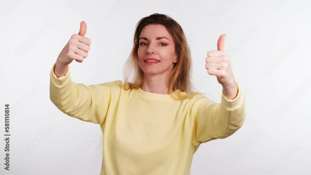 Woman showing thumbs up, yes, winner approving gesture, say Yes, smiling overjoyed. Positive optimistic happy young 20s lady in yellow sweatshirt, excited emotion. Success body language concept Woman showing thumbs up, yes, winner approving gesture, say Yes, smiling overjoyed. Positive optimistic happy young 20s lady in yellow sweatshirt, excited emotion. Success body language concept