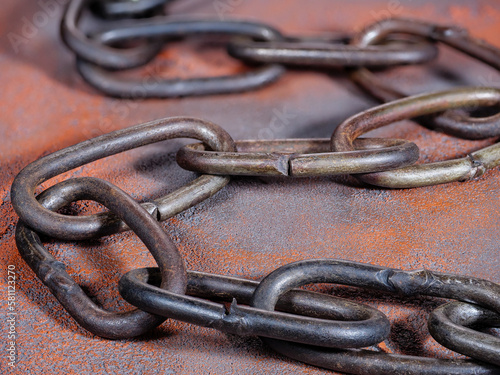 Old rusty link chain on an orange grunge background