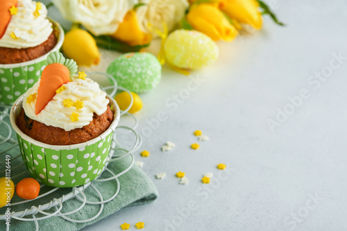 Carrot cake cupcakes for Easter. Carrot cupcakes with cream cheese frosting decorated with tiny marzipan carrots on white background. Happy Easter and spring holiday concept. Holydays homemade dessert