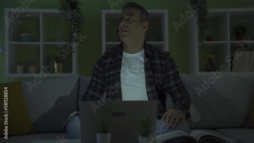 Home office worker man experiencing power outage.
He works at home by looking at files and laptop, but the electricity goes out and his work is interrupted.
