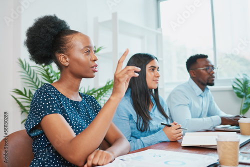 Young business woman raises hand in boardroom meeting to ask question