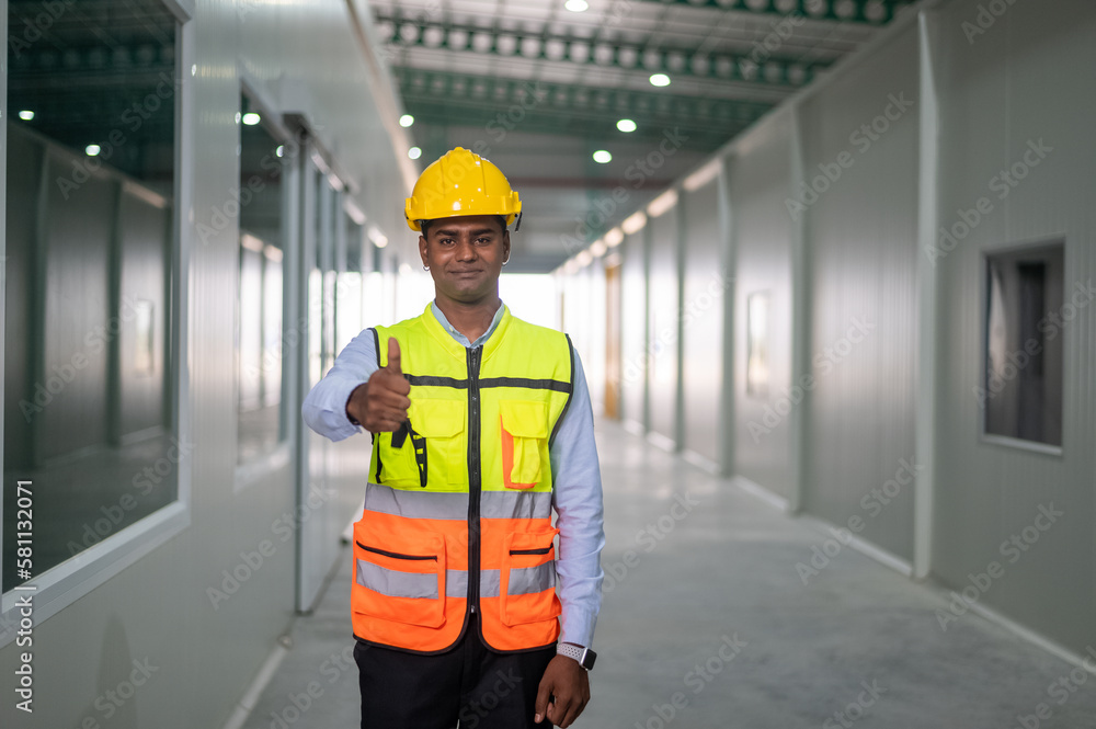 Indian worker standing confident in factory background Indian worker standing confident in factory background