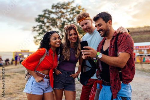 Cheerful friends using phone at festival