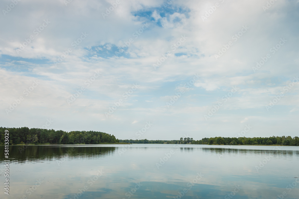 Landscape with a forest lake. Reflection of clouds in the lake. Summer